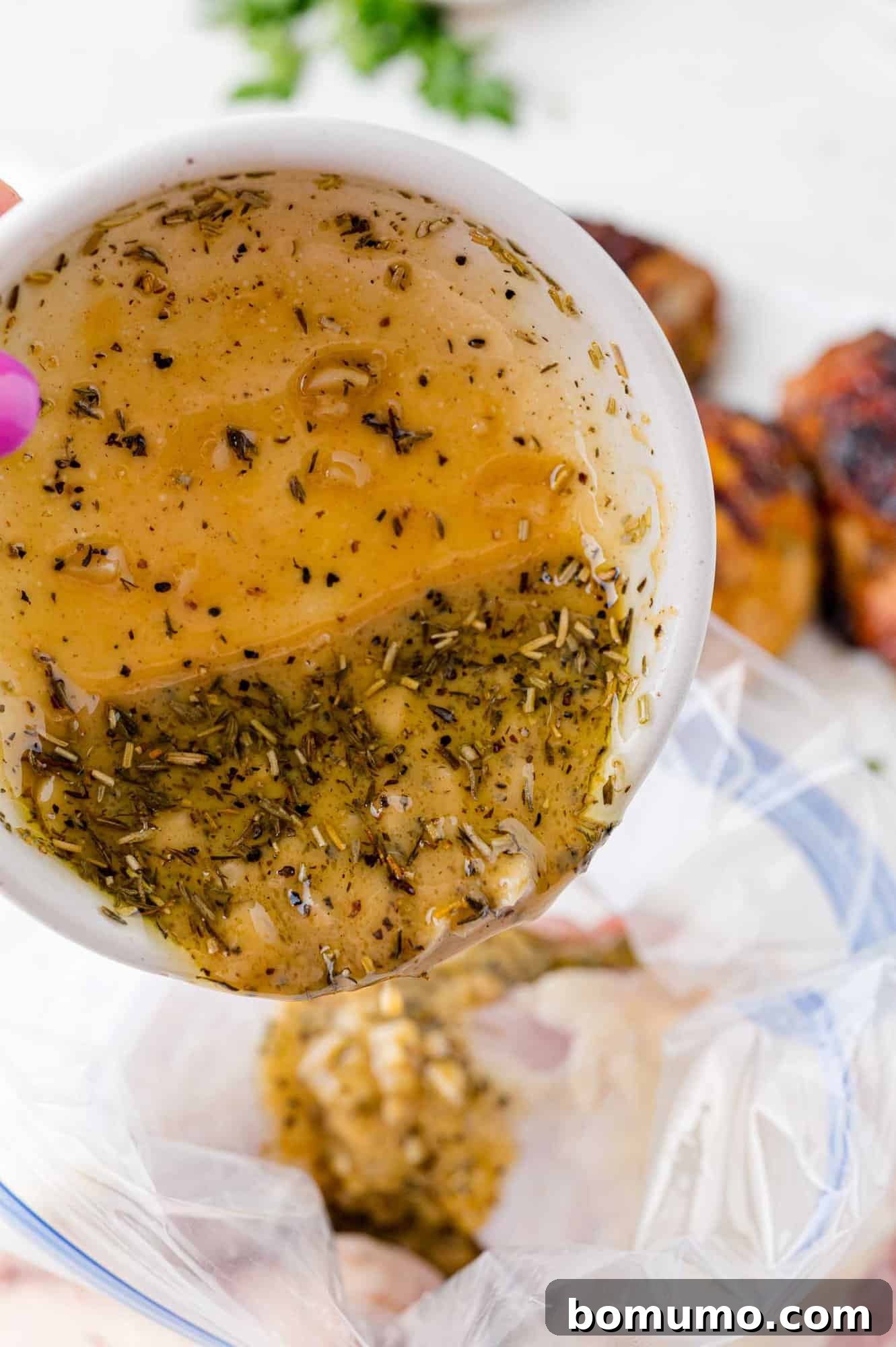 The marinade being poured into a zip-top bag with chicken thighs, ready for an efficient marinating process.