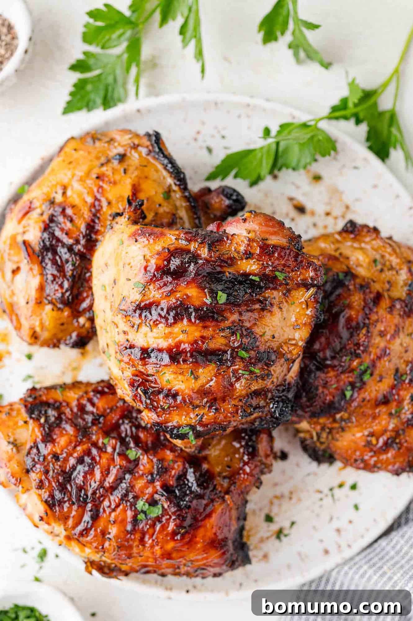 Two perfectly grilled chicken thighs resting on a white plate, ready to be served.