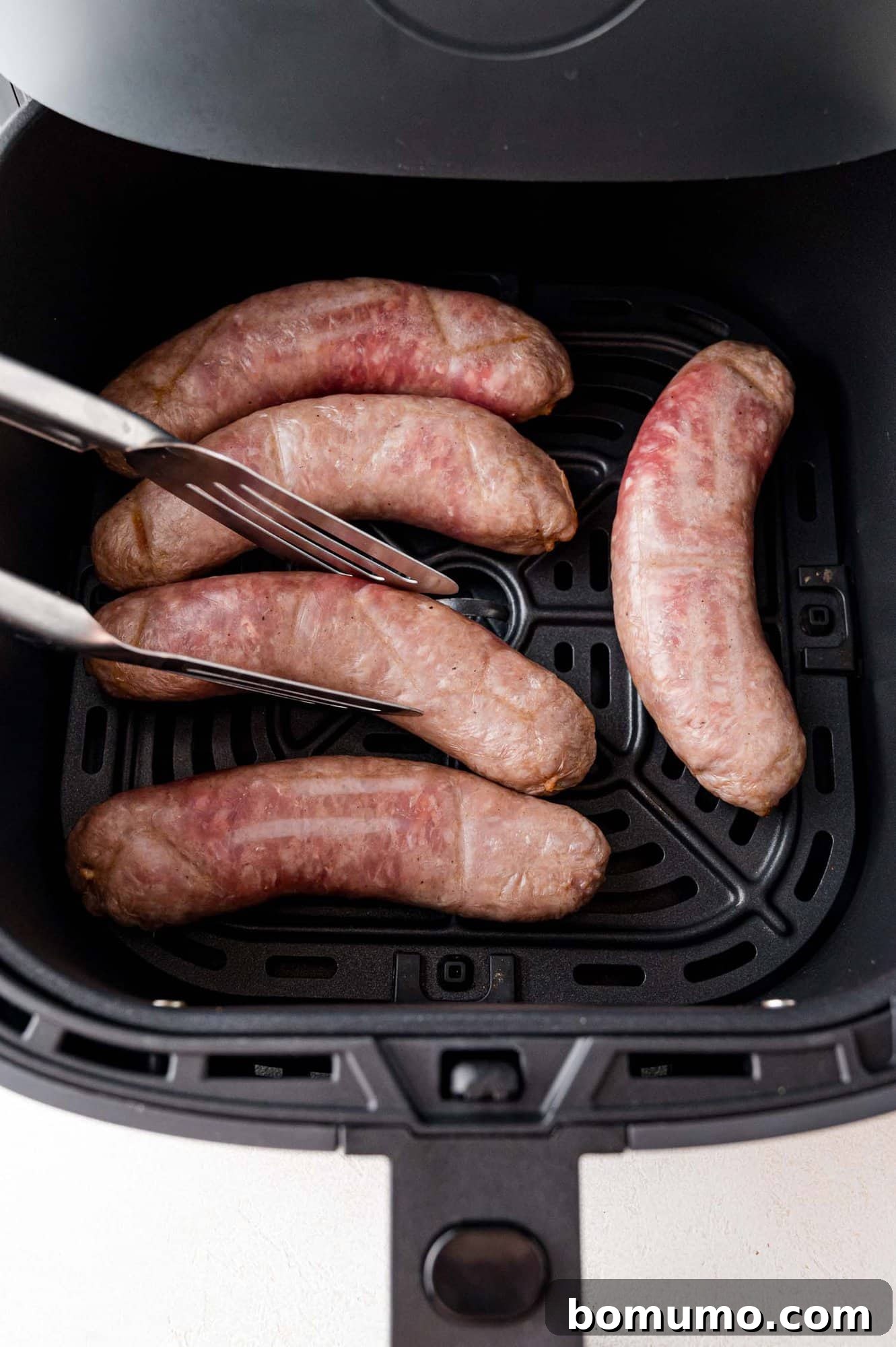 Brat being flipped over in an air fryer