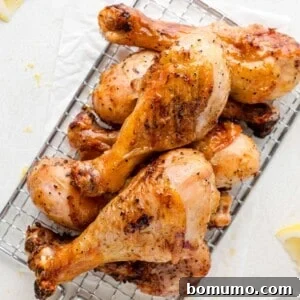 Stack of grilled chicken drumsticks piled up, lemon wedges also visible.