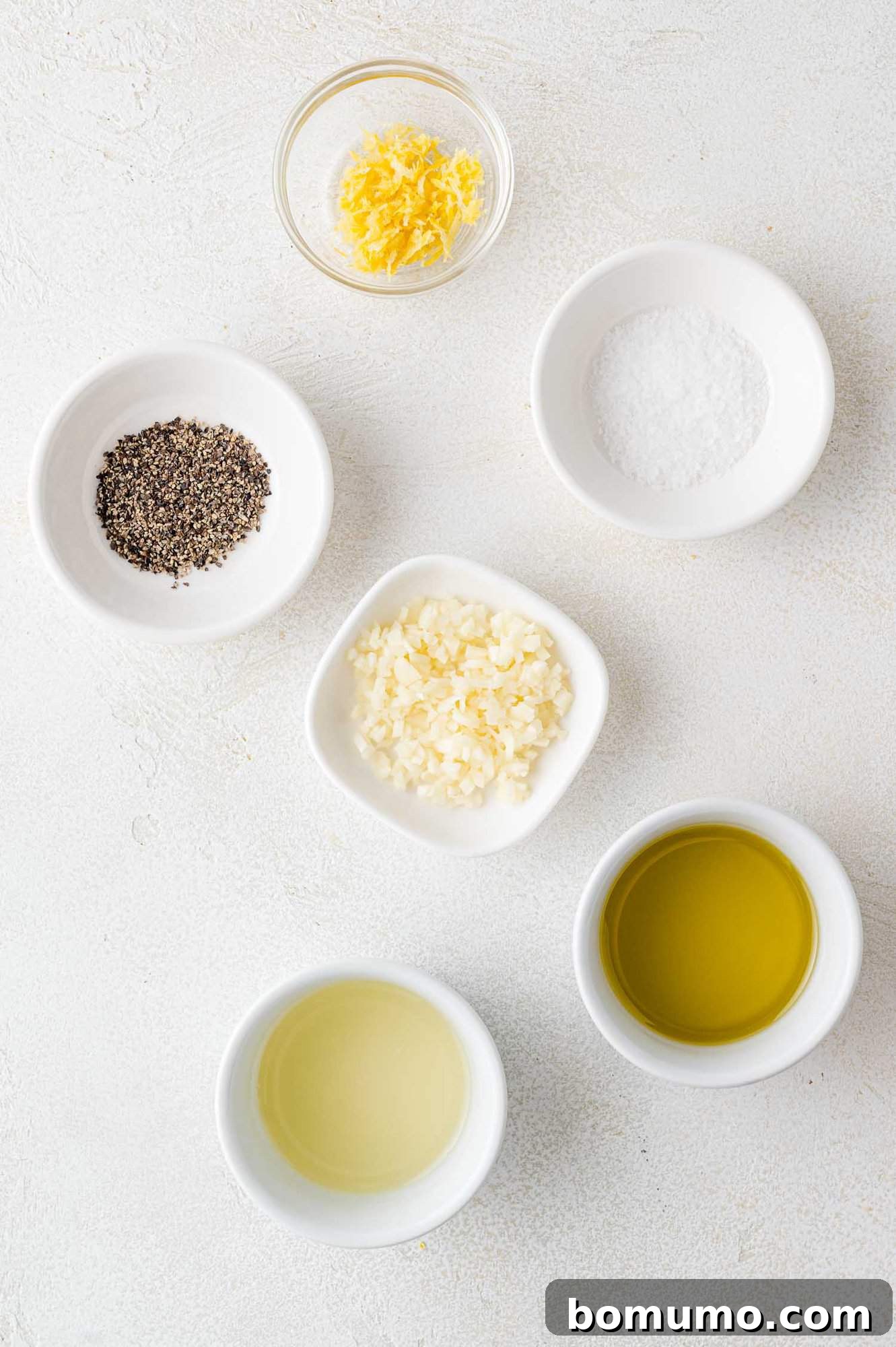 A collection of fresh ingredients, including lemons, garlic, and a bottle of olive oil, neatly arranged to make the lemon pepper chicken marinade.