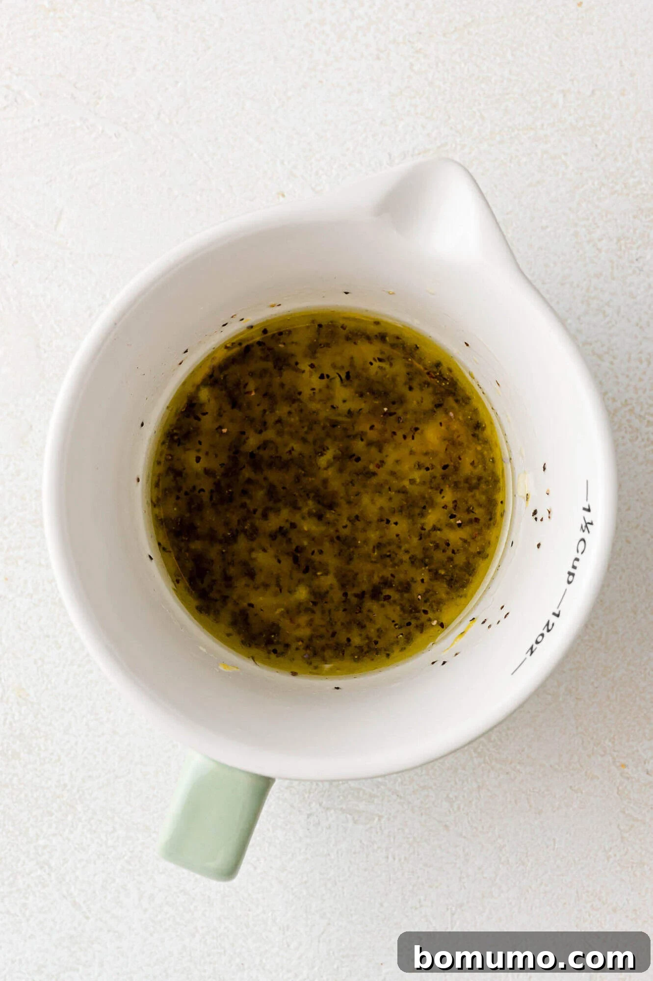 The vibrant lemon pepper marinade ingredients, perfectly mixed and ready, sitting in a clear measuring cup.