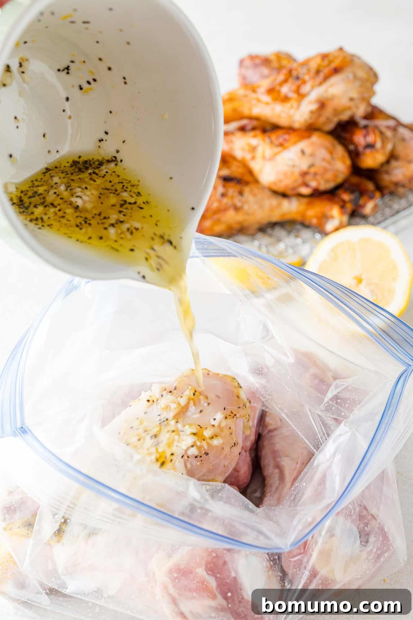 The zesty lemon pepper marinade being poured over raw chicken drumsticks nestled inside a zip-top bag, ensuring every piece is coated.
