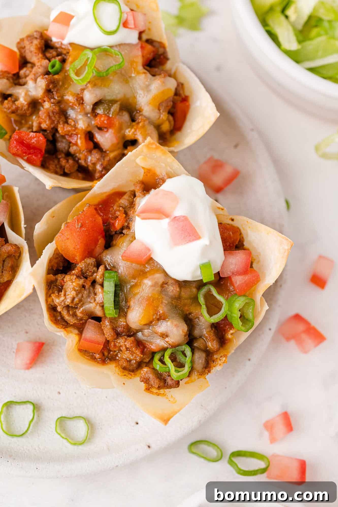 Overhead view of wonton taco cup, topped with sour cream and green onions.