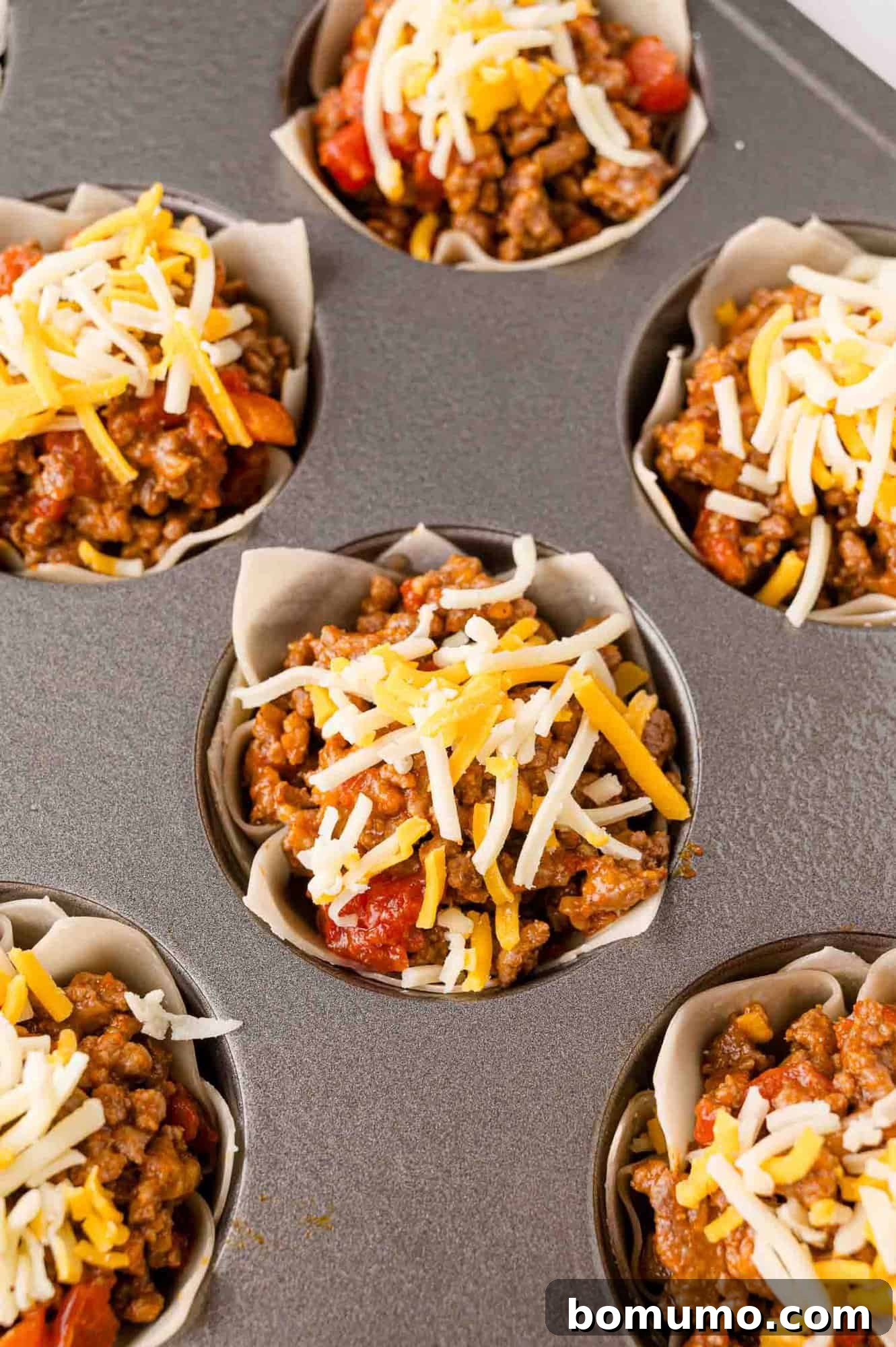 Cheese added to uncooked wonton taco cups.