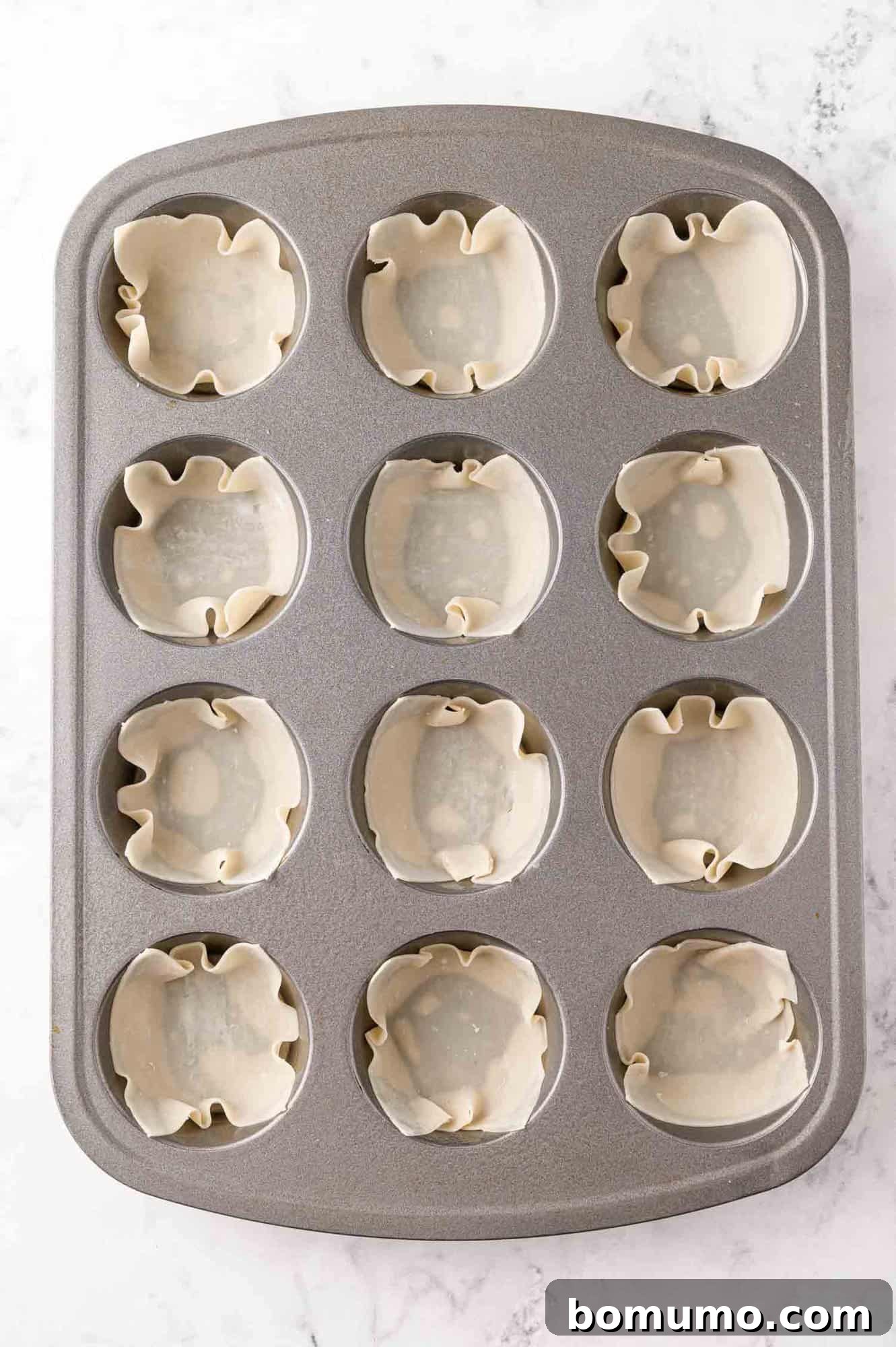 Wonton wrappers pressed into a muffin tin.