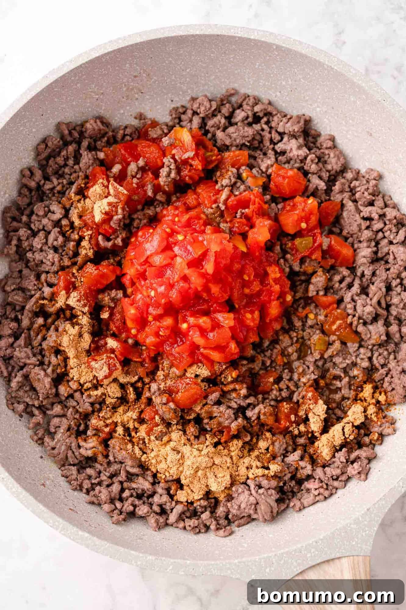 Tomatoes and taco seasoning added to meat mixture.