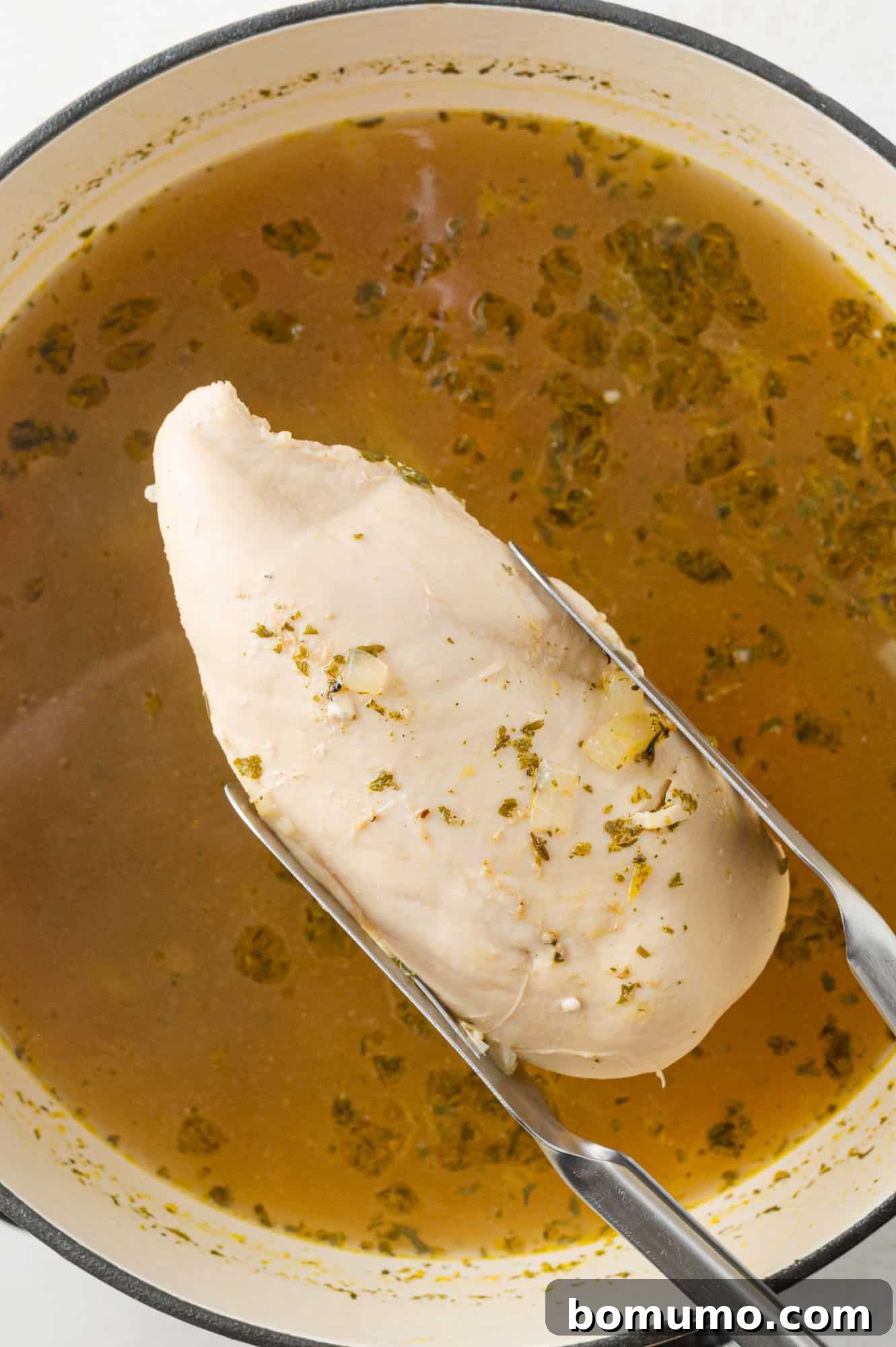 Chicken being removed from pan.