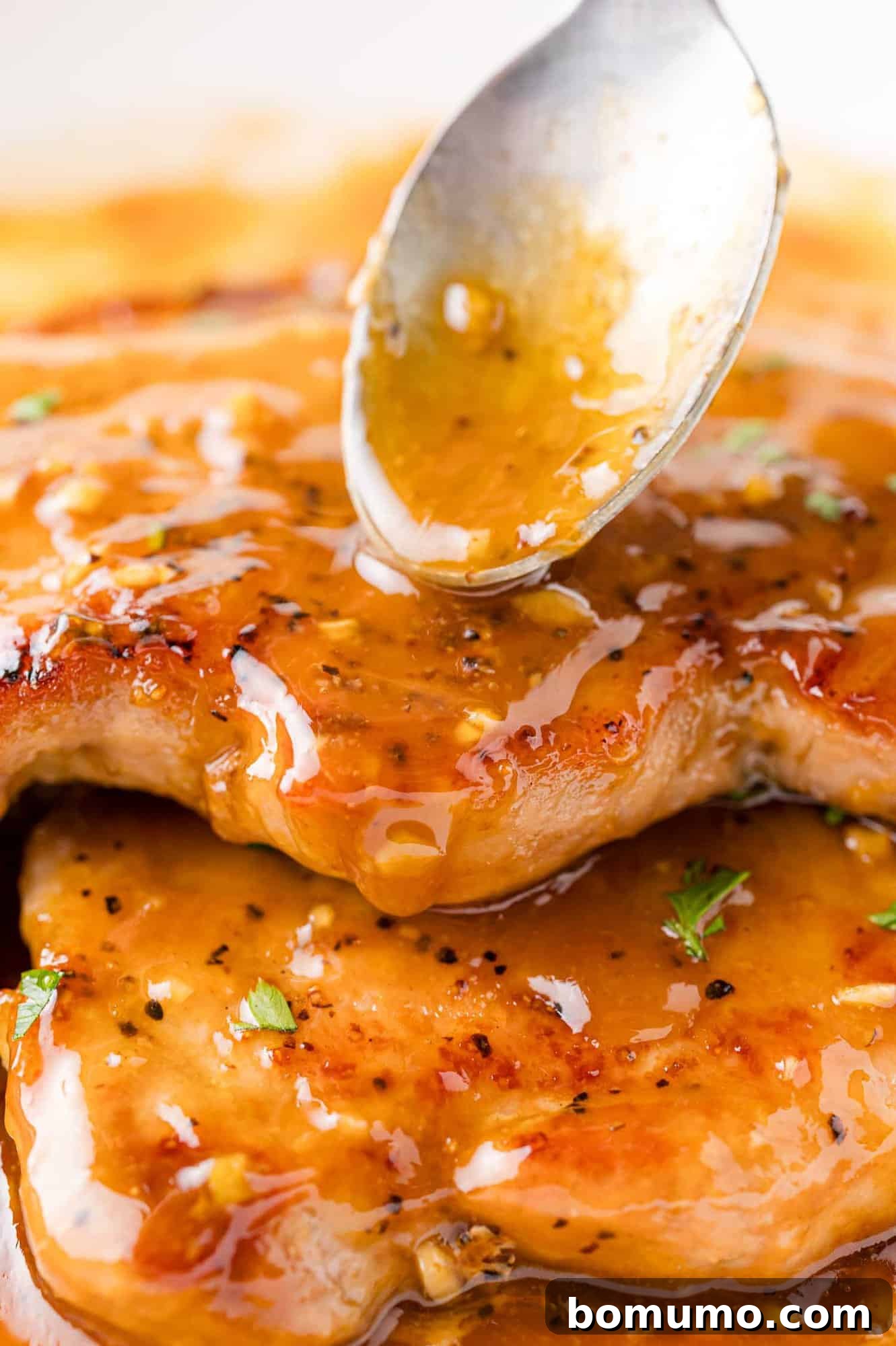 Sauce being spooned onto honey garlic pork chops, emphasizing the glaze.