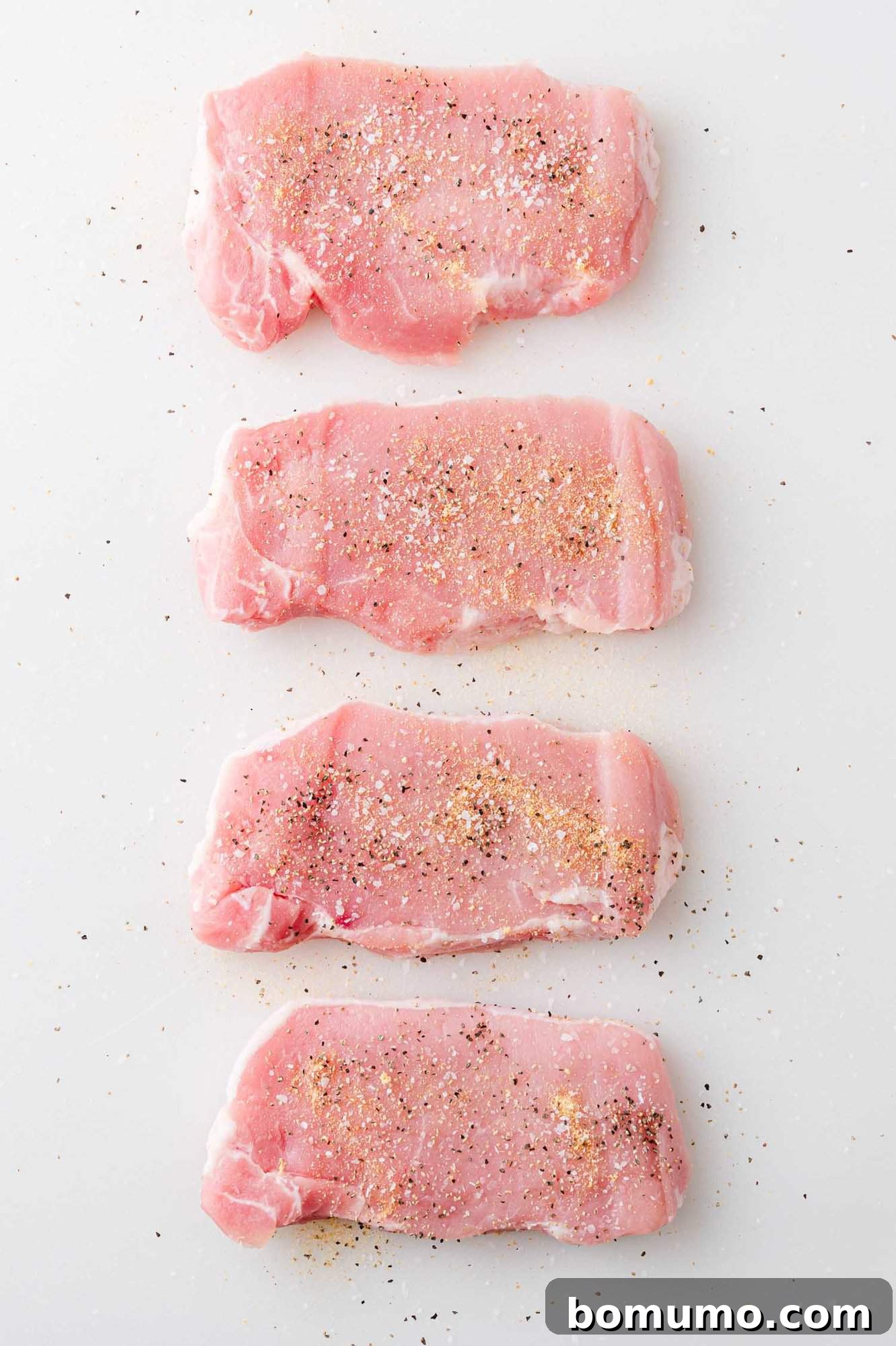 Uncooked pork chops, seasoned with spices.