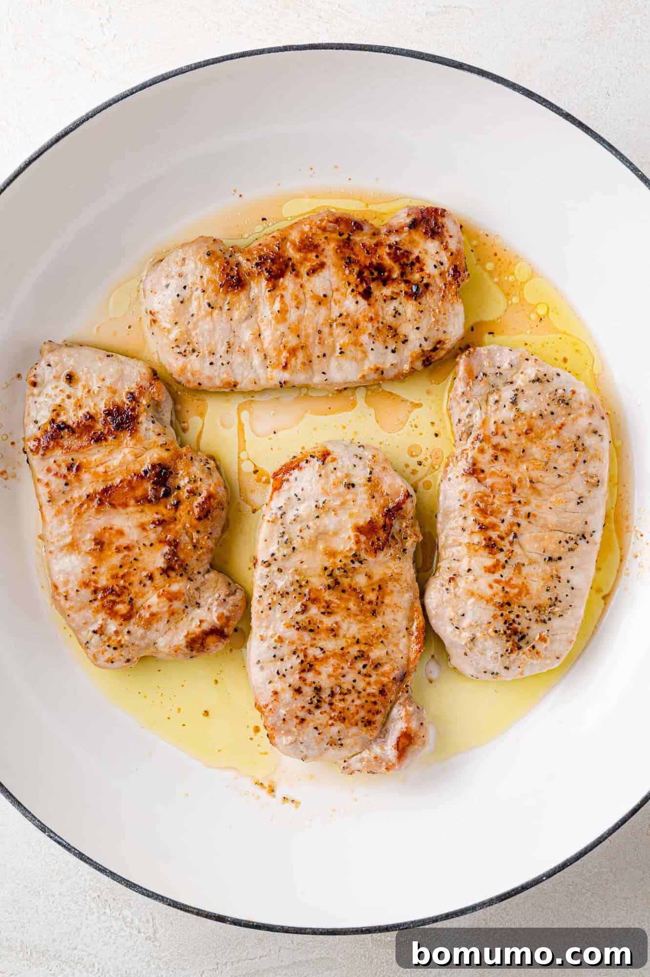 Cooked pork chops browning beautifully in the pan.