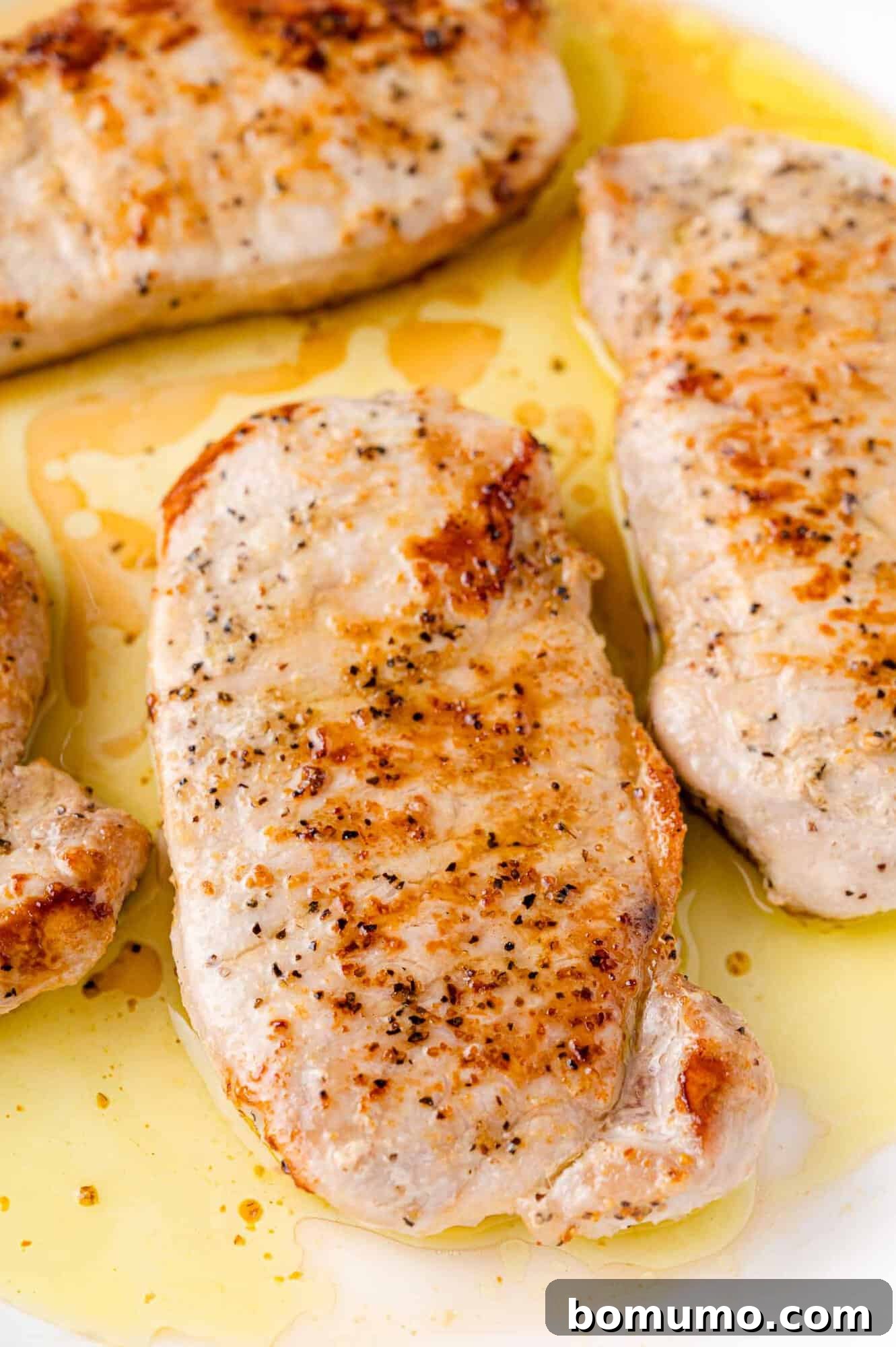 Another view of cooked pork chops in the pan, golden brown.