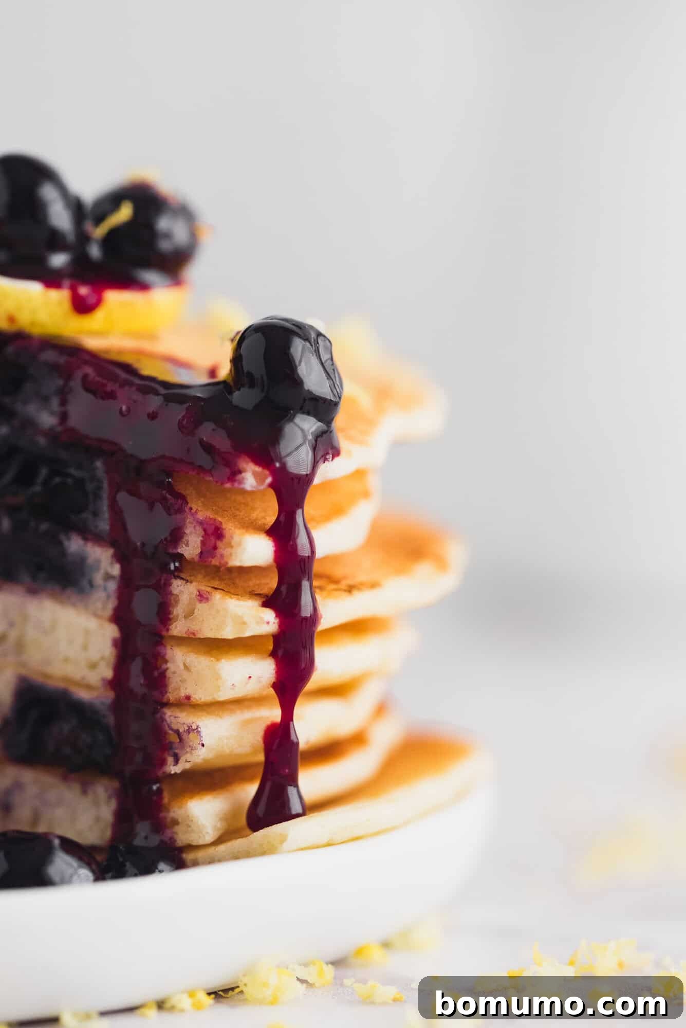 Luscious Blueberry Compote 2 Homemade blueberry sauce cascading beautifully down the side of a tall stack of golden pancakes, ready to be enjoyed.