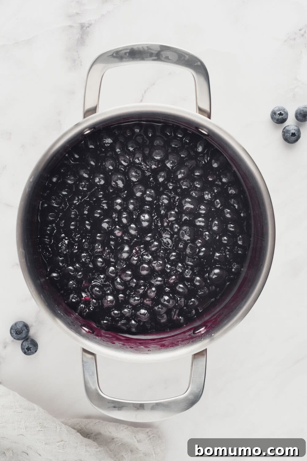 Luscious Blueberry Compote 6 Blueberry sauce in the pan after it has been cooked, showcasing its thickened, vibrant purple texture.