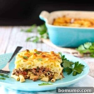 Front view of plated pastitsio with casserole dish in background.