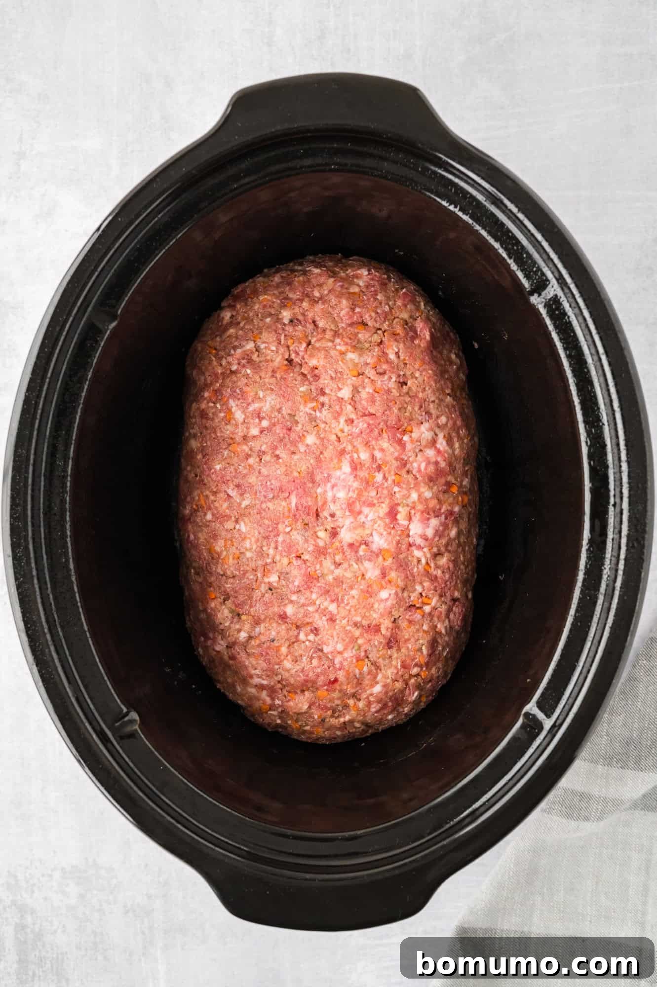 The shaped meatloaf carefully placed inside the slow cooker, ready for cooking.