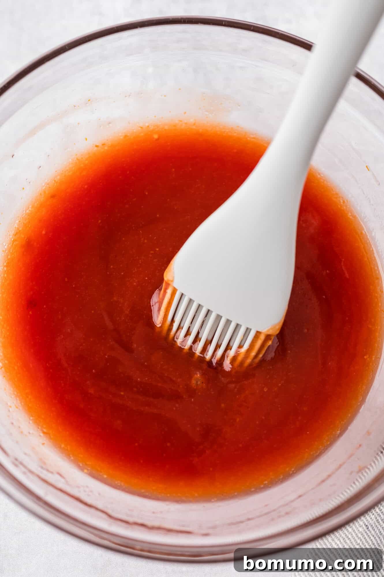 The mixed glaze ingredients in a small glass bowl, a thick and shiny consistency.