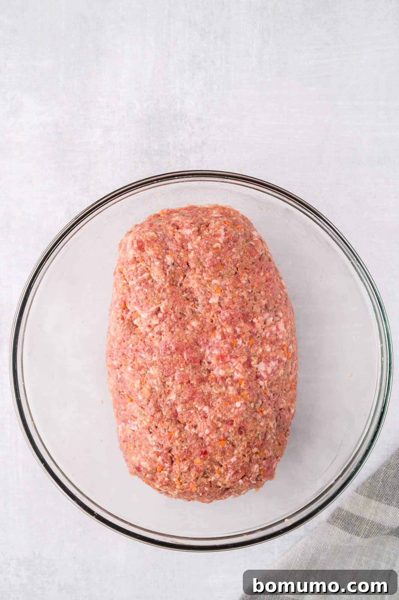 Meatloaf mixture shaped into a neat loaf within a glass bowl, ready for transfer.