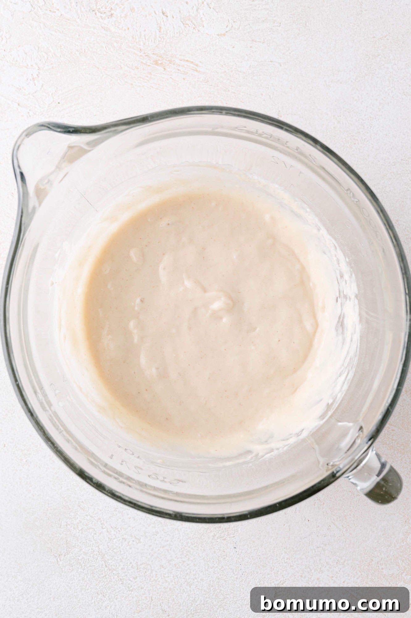 Completed buttermilk pancakes batter in a clear glass bowl.