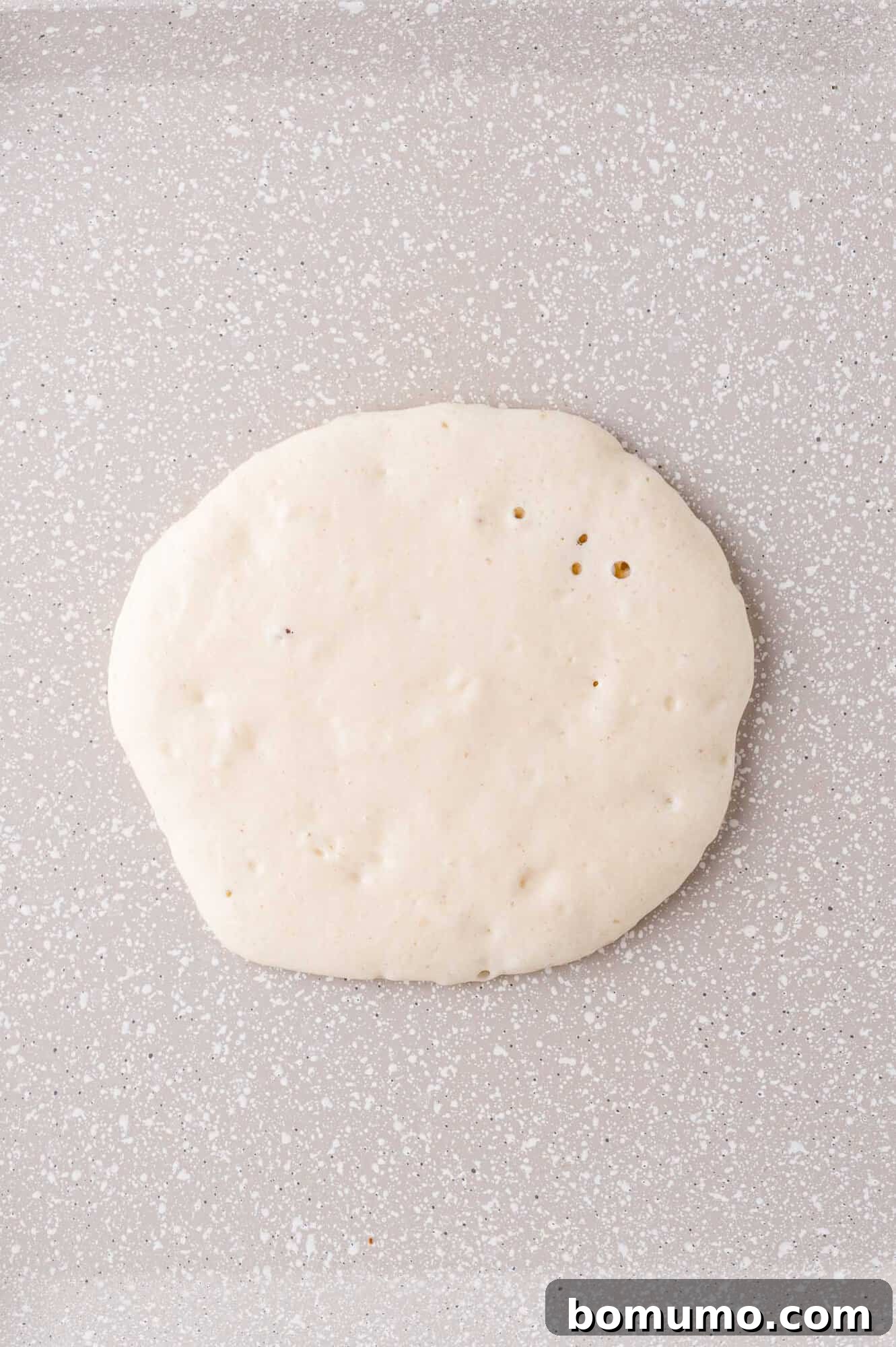 Pancake on griddle, not yet cooked.