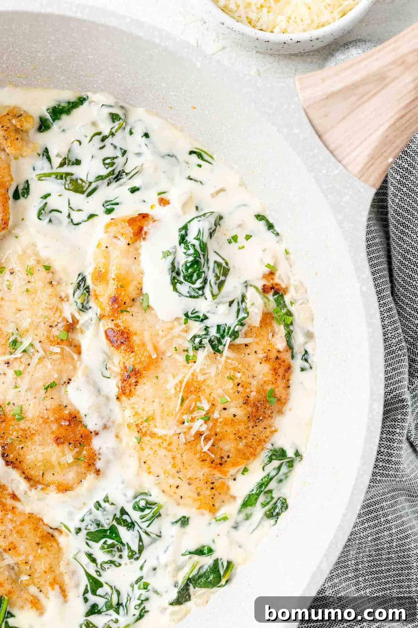 Silken Florentine Chicken 3 Golden-brown chicken cutlets nestled in a vibrant spinach cream sauce within a white skillet.