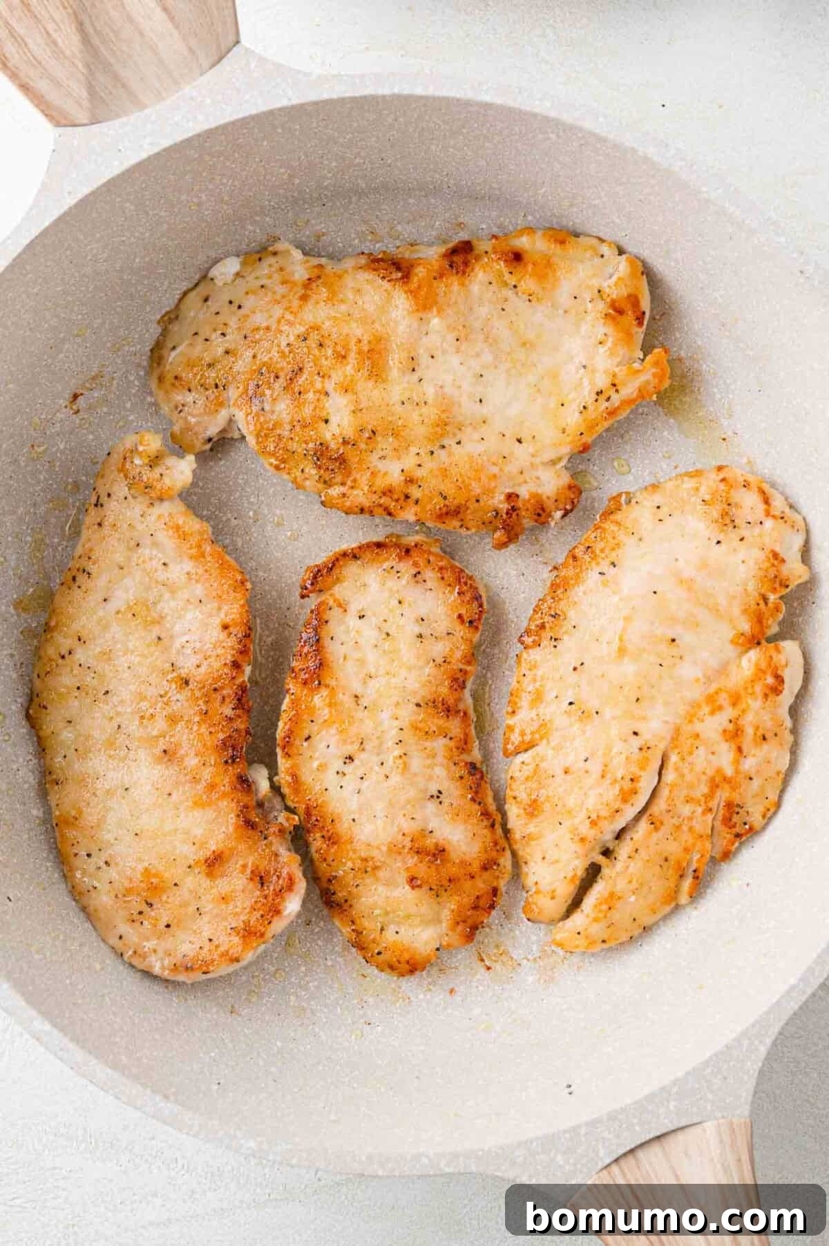 Silken Florentine Chicken 7 Perfectly browned chicken cutlets resting in a clean white pan after being seared to perfection.