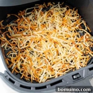 Crispy hash browns, in an air fryer basket, ready to be served.