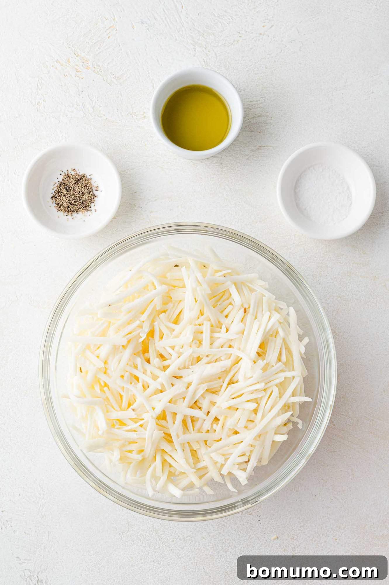 Overhead view of all ingredients needed for crispy air fryer hash browns recipe, including frozen shredded potatoes, olive oil, and seasonings.