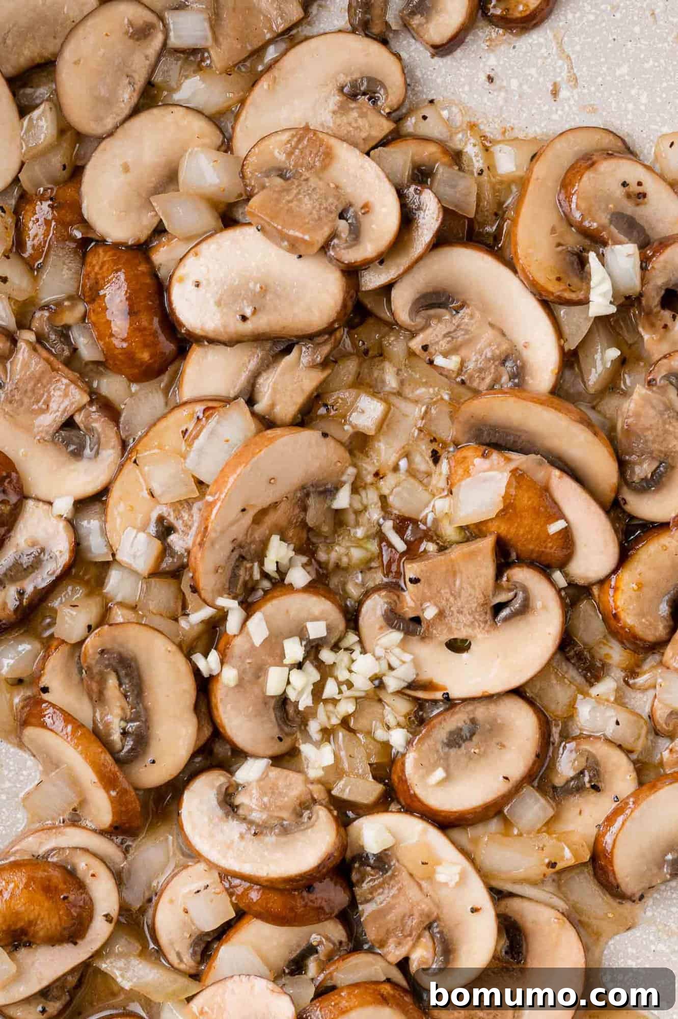 Minced garlic freshly added to the pan with sautéed mushrooms and onions.