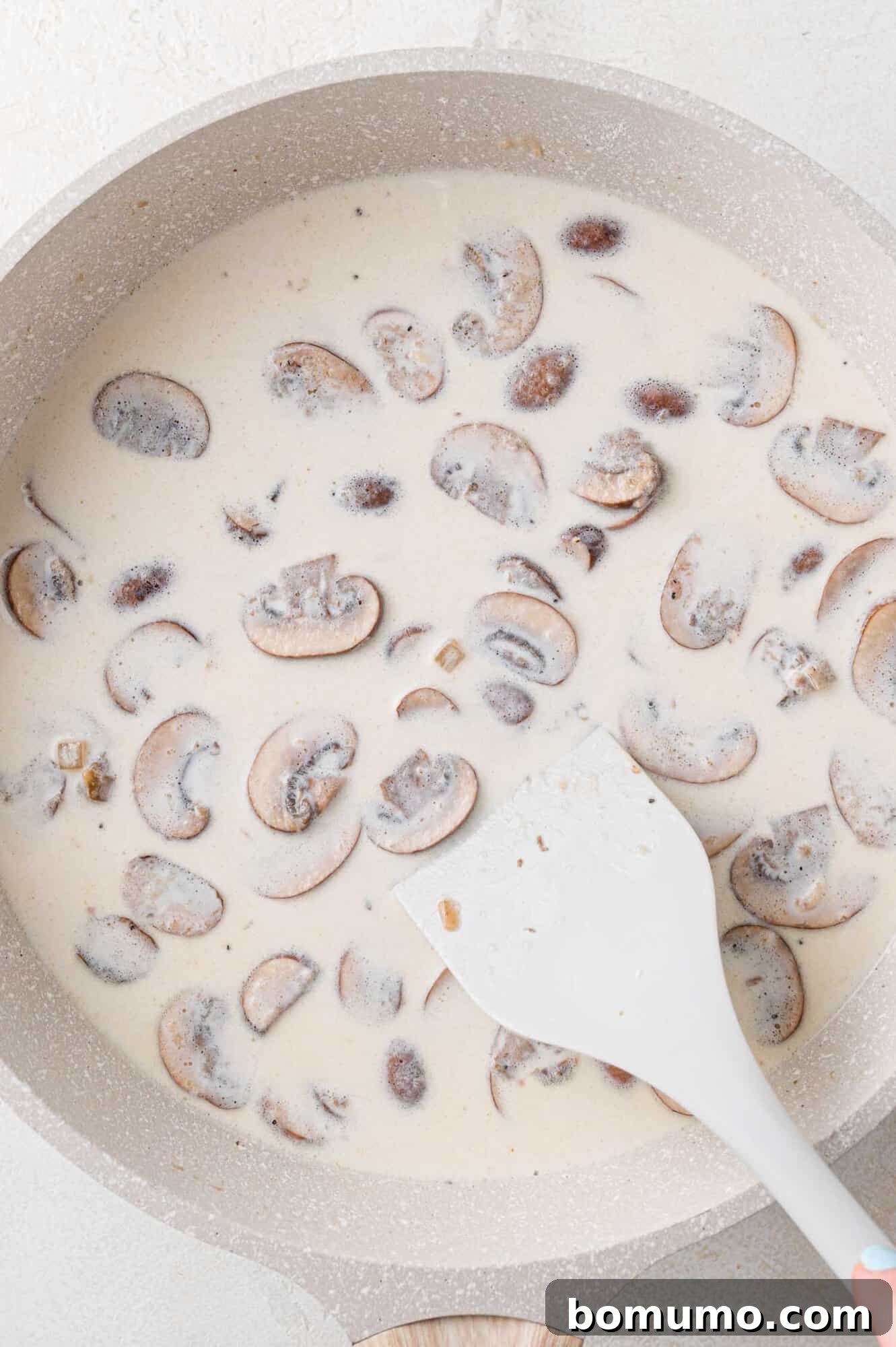 Chicken broth and half-and-half being poured into the skillet with the flour-coated vegetables.