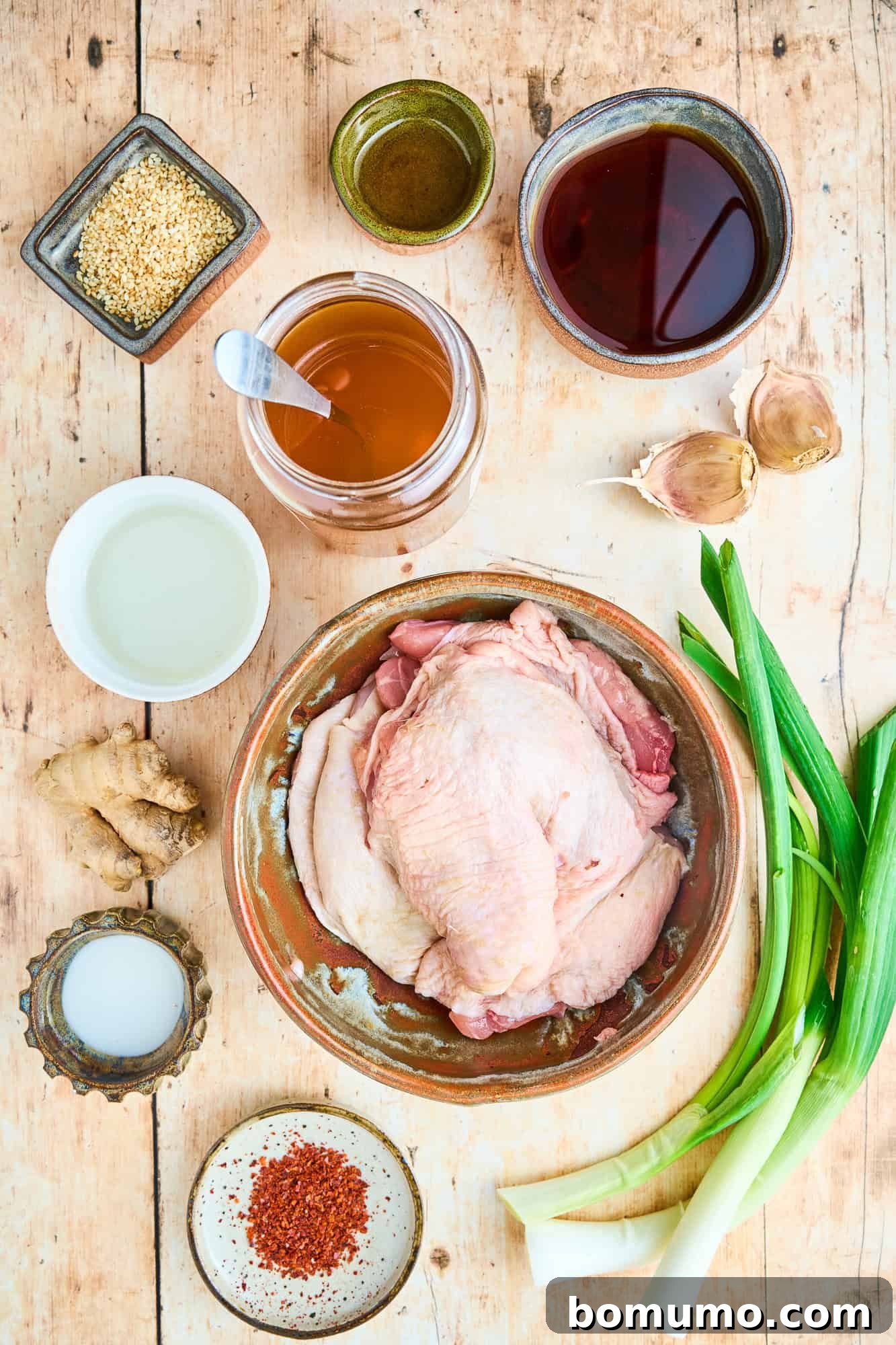 An inviting overhead view of all the fresh ingredients carefully laid out on a kitchen counter, ready for preparing the crispy ginger chicken thighs. Includes bottles of soy sauce, honey, fresh ginger, garlic, and chicken thighs.