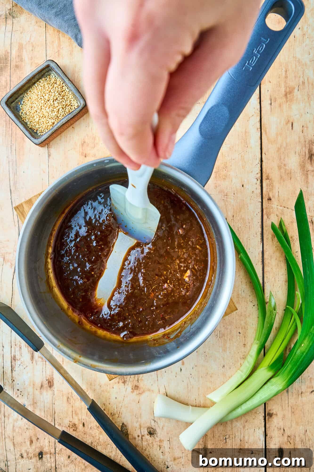 The rich, glossy ginger sauce, perfectly thickened, with a spatula running through it to showcase its sticky, luscious texture.