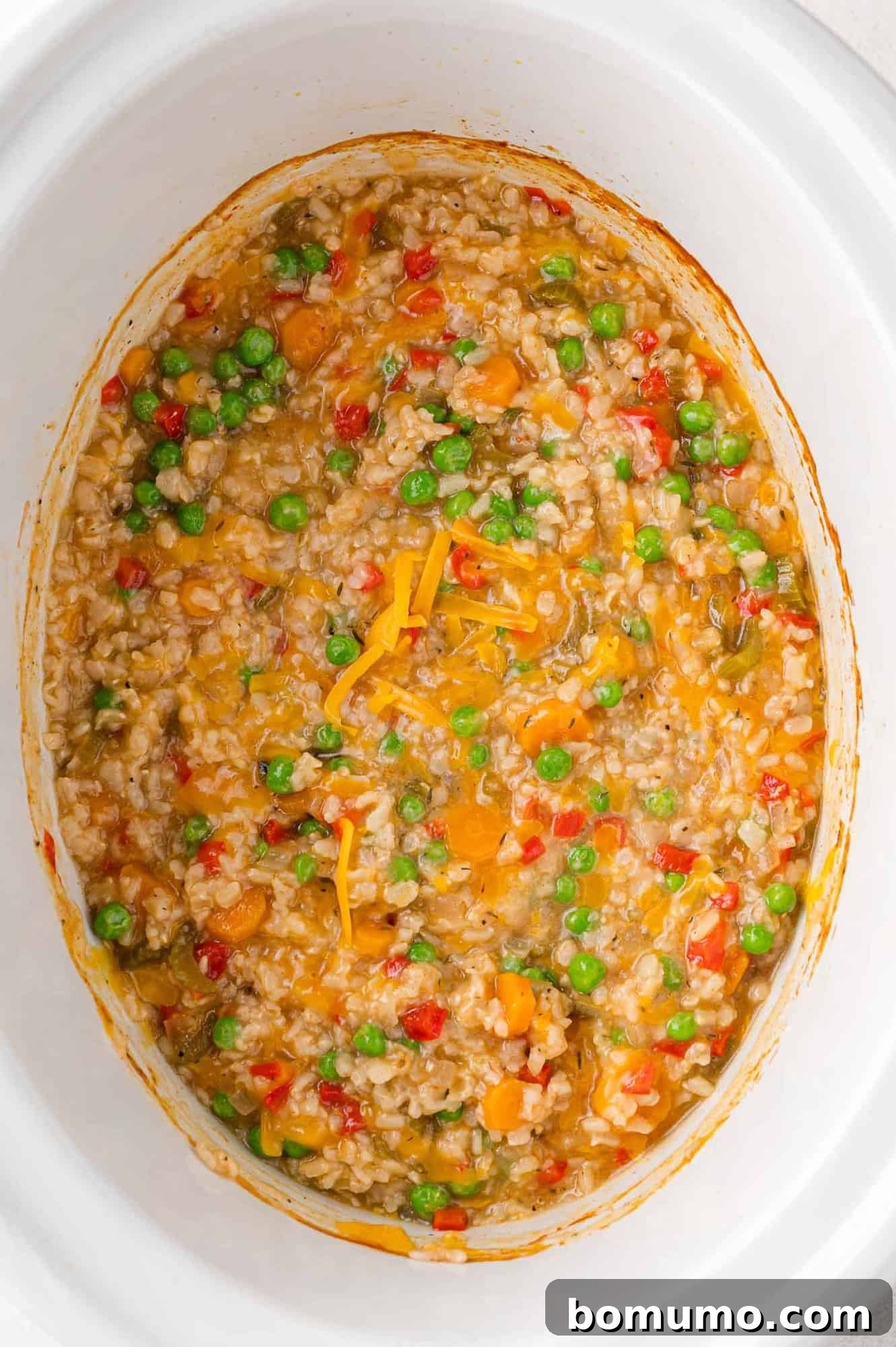 The Crockpot chicken and rice is fully cooked, waiting for the chicken to be shredded and peas/cheese to be added.