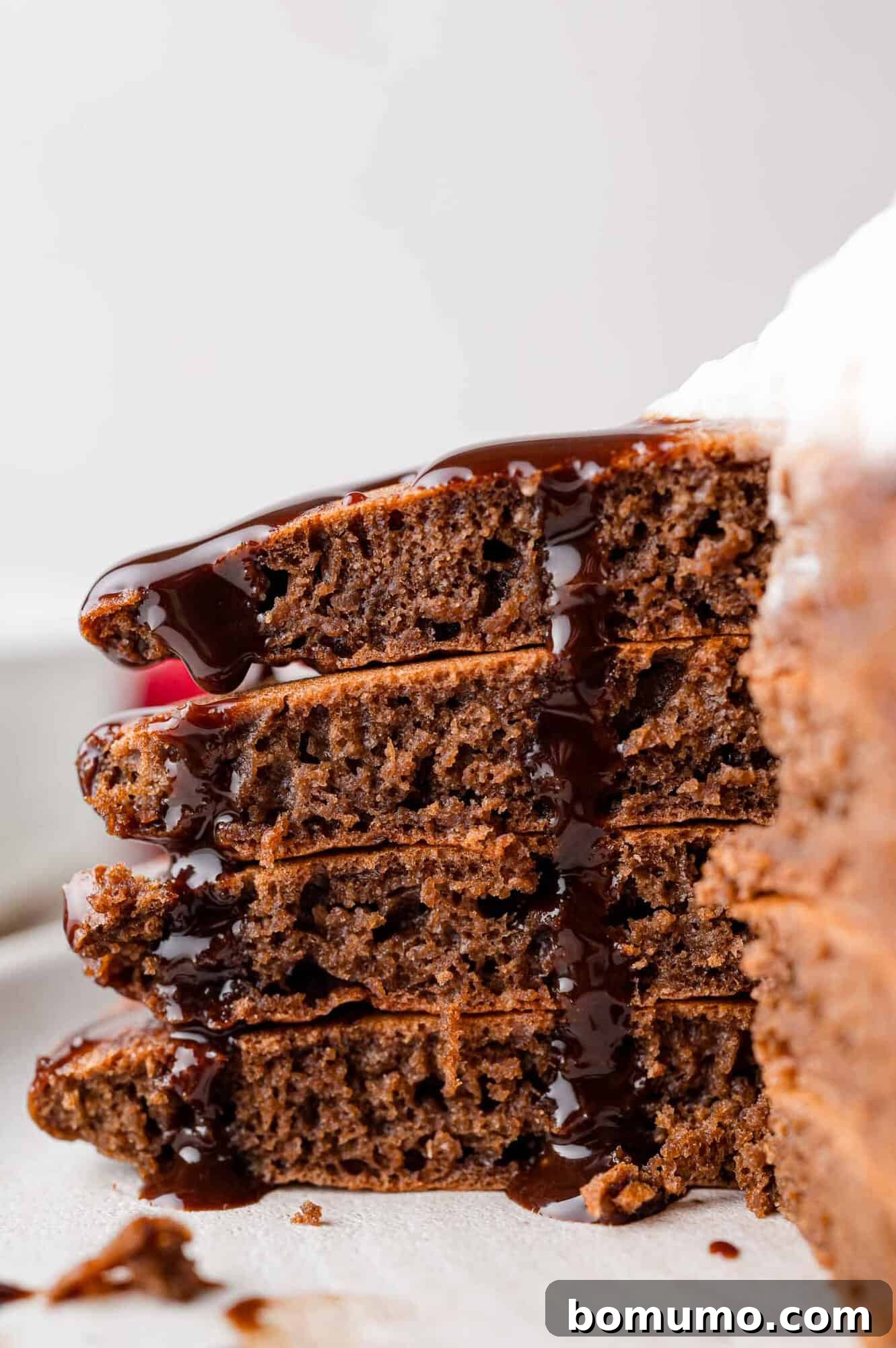 Decadent Chocolate Flapjacks 13 A stack of chocolate pancakes, sliced open, with rich chocolate syrup elegantly dripping down the sides.