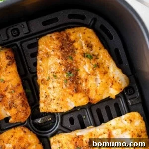 Close-up of seasoned fish fillets in an air fryer basket, with a golden-brown, crispy texture.