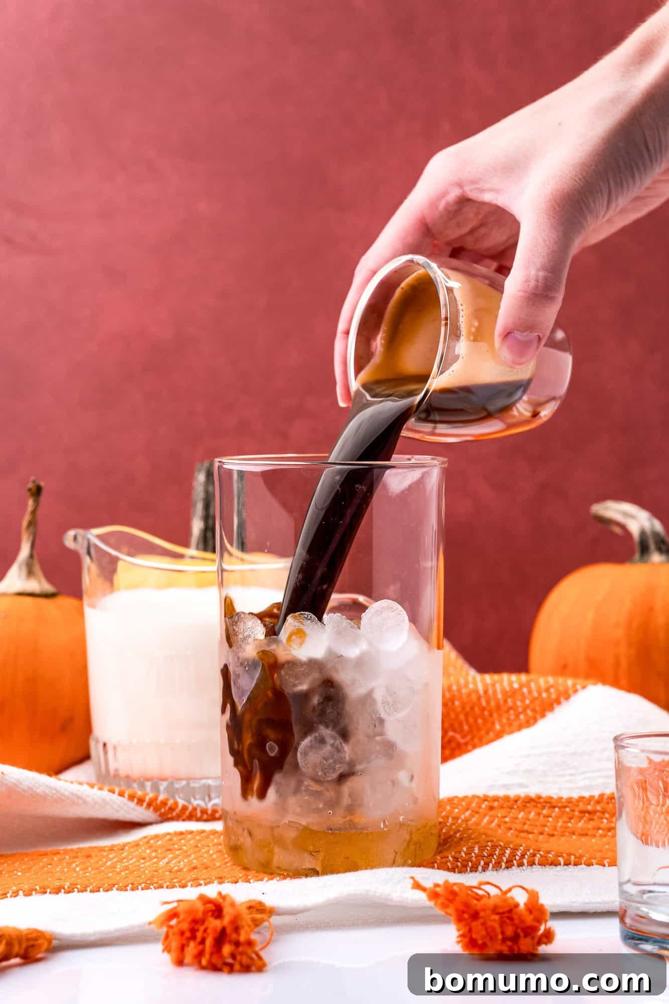 Freshly brewed espresso being poured over ice in a glass, ready to be combined with other ingredients.