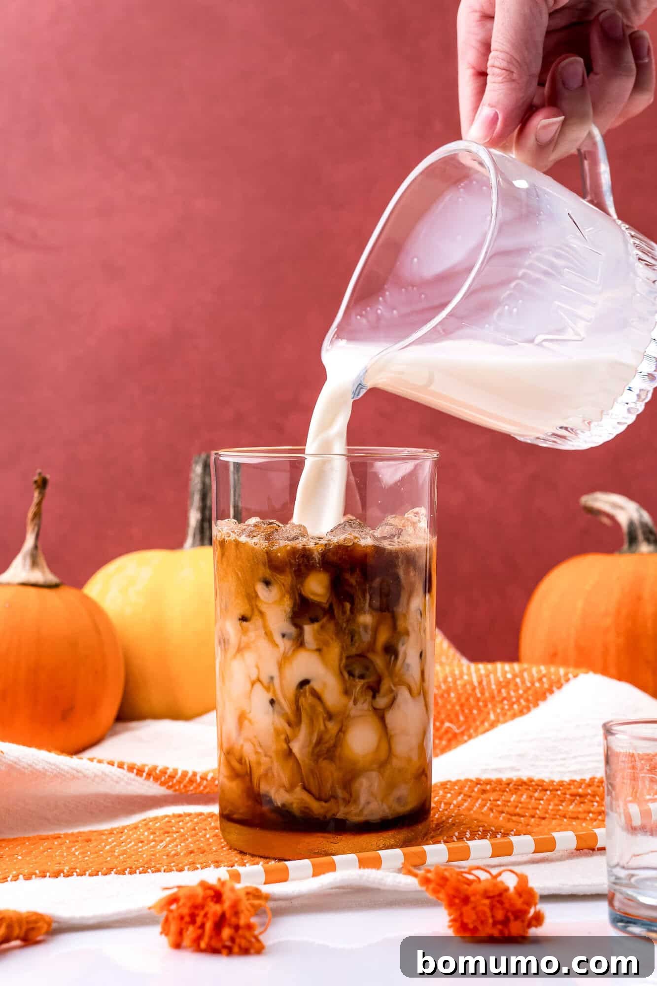 More milk being poured into the iced latte, ensuring a perfect balance and creamy consistency.