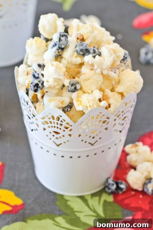 Blueberry Cream Pop 4 Blueberry and Cream Popcorn in a decorative cup, on a floral cloth.