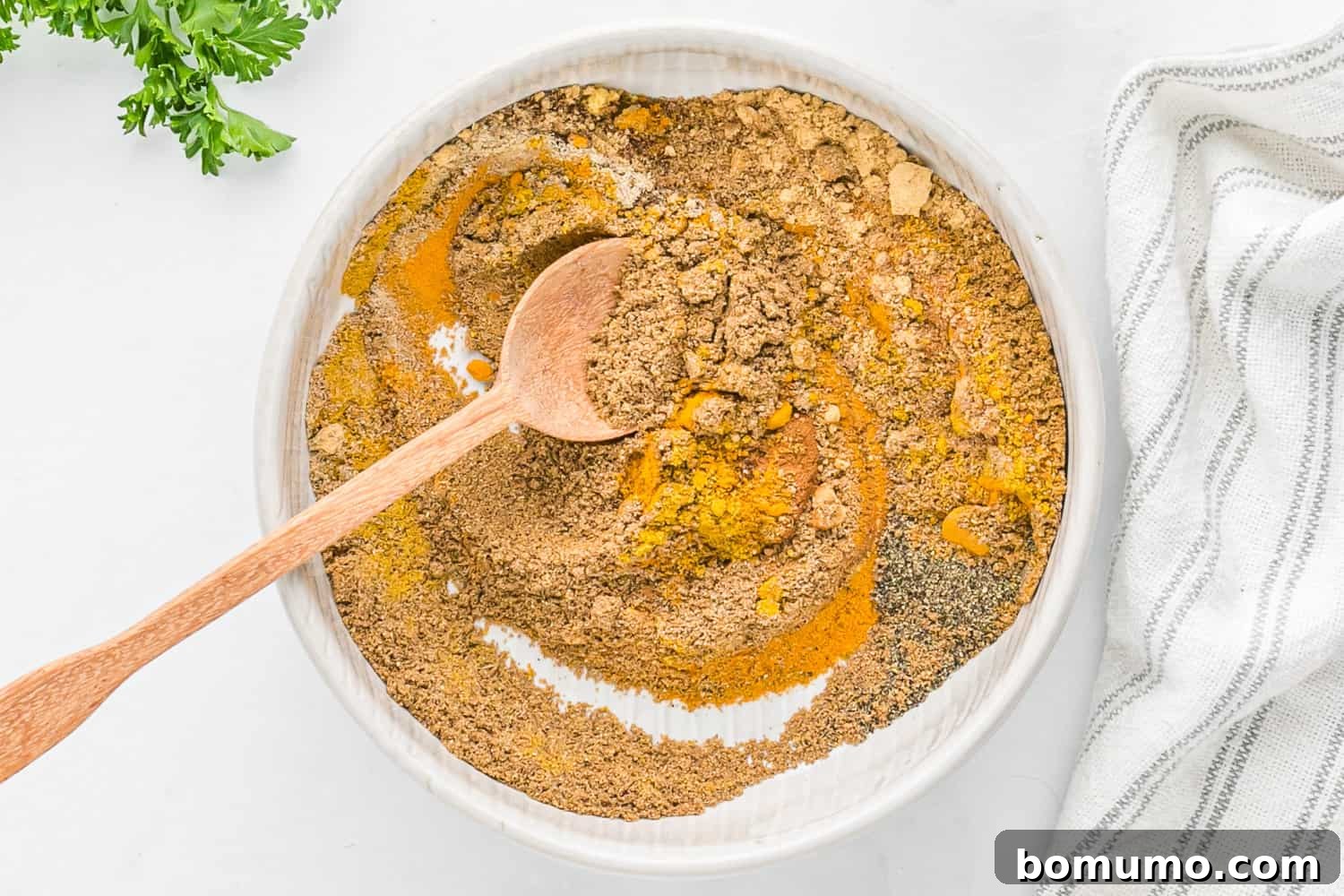 Spices partially mixed in a bowl, showing the vibrant colors beginning to merge.