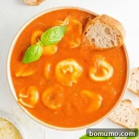 Crockpot tomato soup with cheese tortellini, garnished with fresh basil.