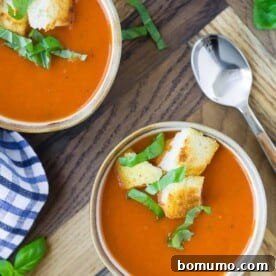 Overhead view of three small bowls of instant pot tomato soup, topped with croutons and fresh basil.
