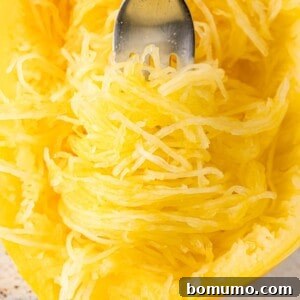 Spaghetti squash nearly filling the frame, some wrapped around a fork, some still in peel of squash.