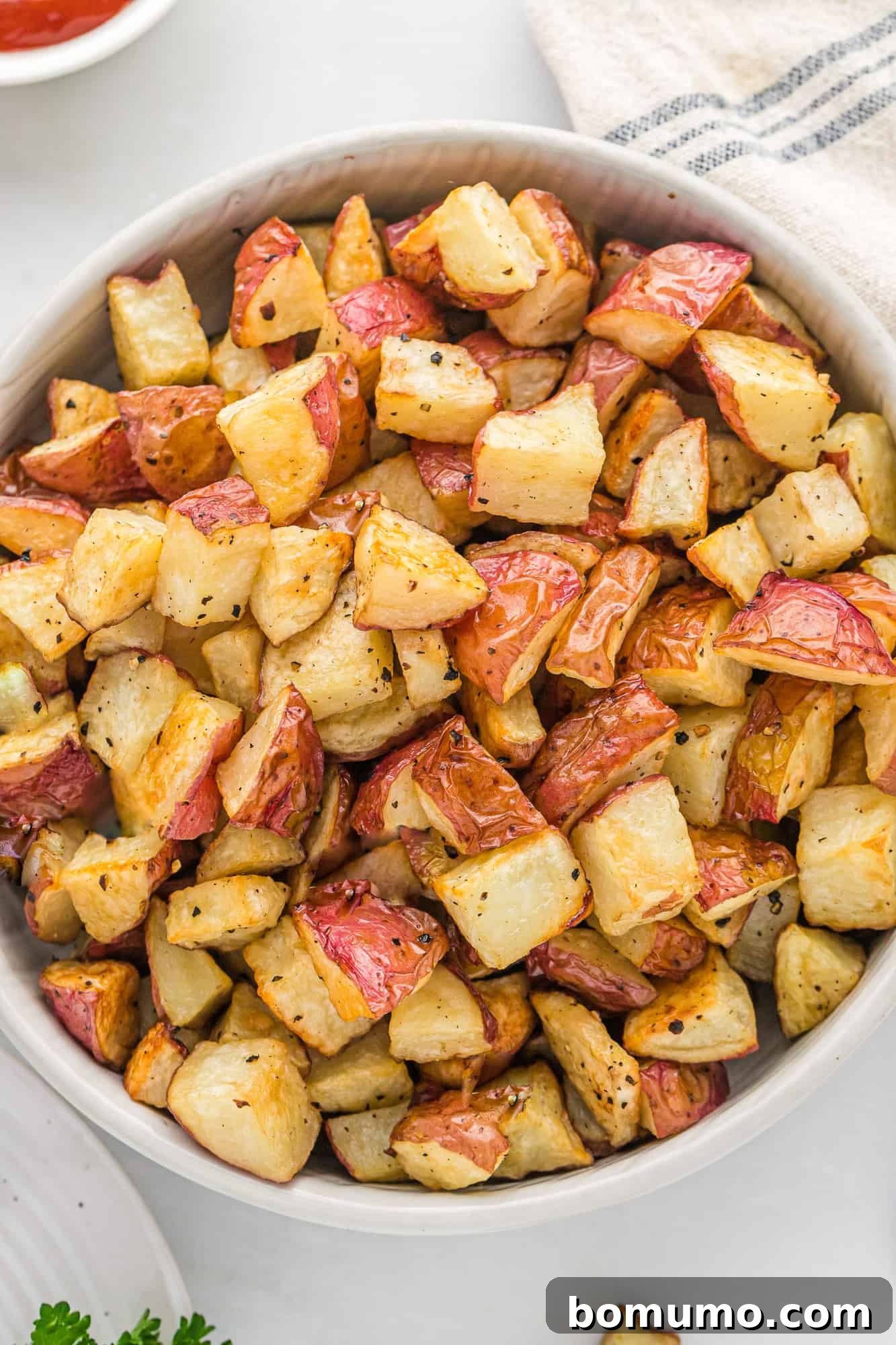 Close up of a large bowl of irresistibly crispy roasted potatoes, perfectly golden brown and seasoned.