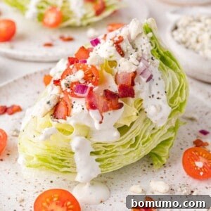 A wedge salad topped with blue cheese dressing, bacon bits, cherry tomatoes, and chopped red onions on a speckled plate.