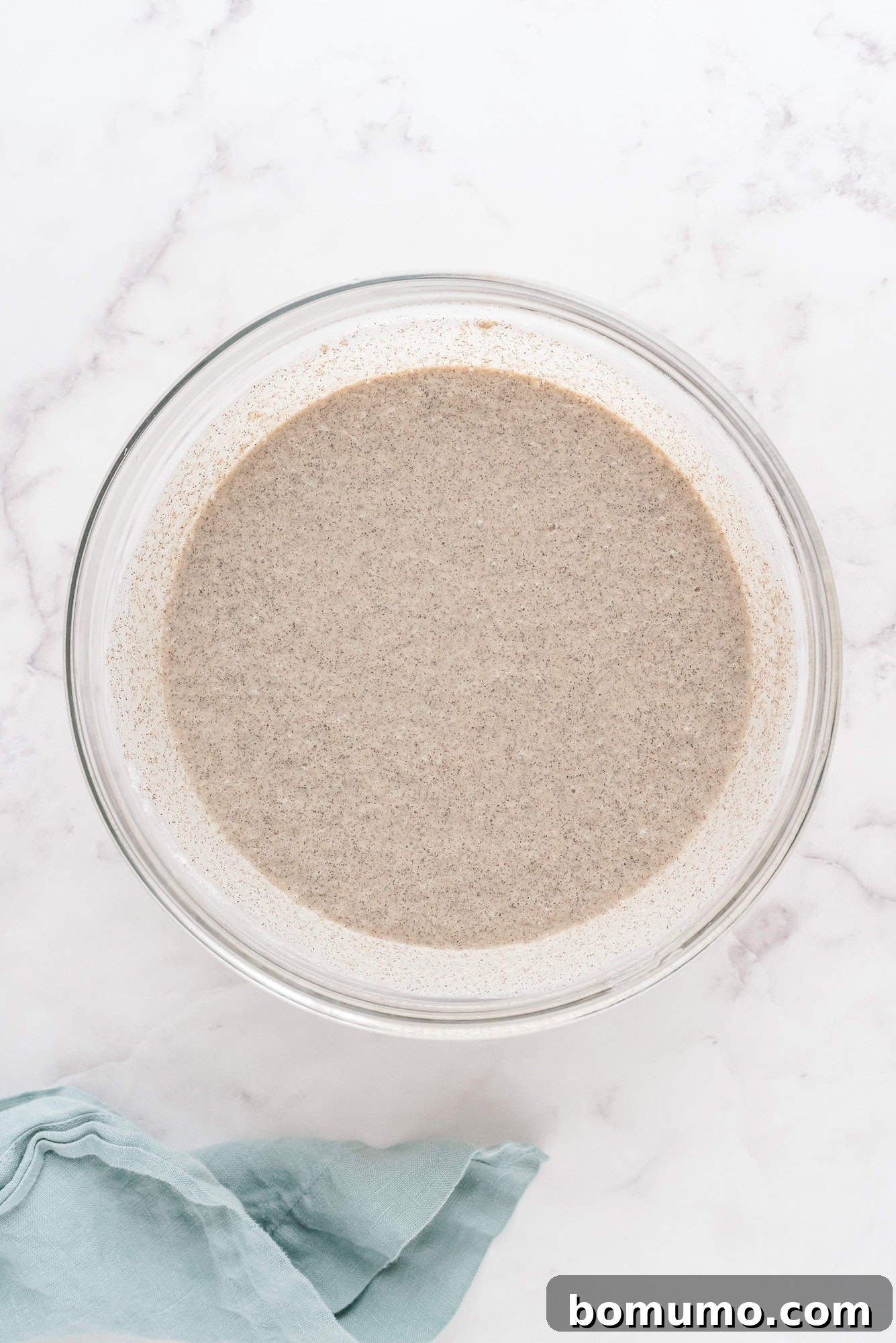The freshly prepared pancake batter, smooth with a few small lumps, resting in a clear mixing bowl, ready for cooking.