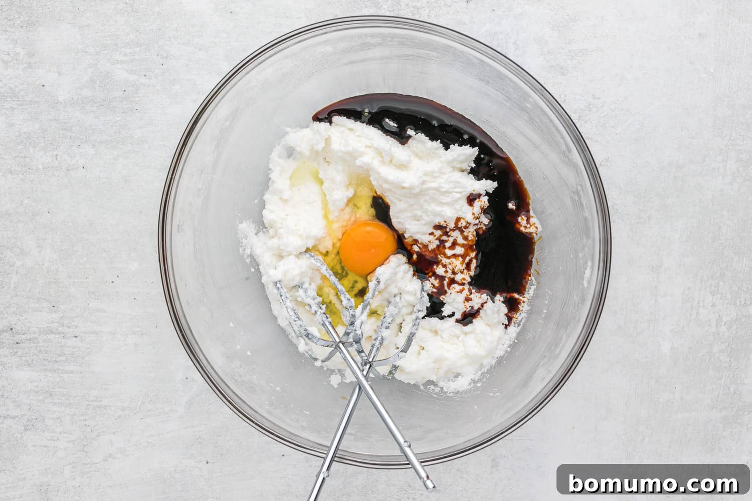 Wet ingredients including molasses and egg in a clear glass bowl, ready to be mixed into the creamy shortening and sugar.