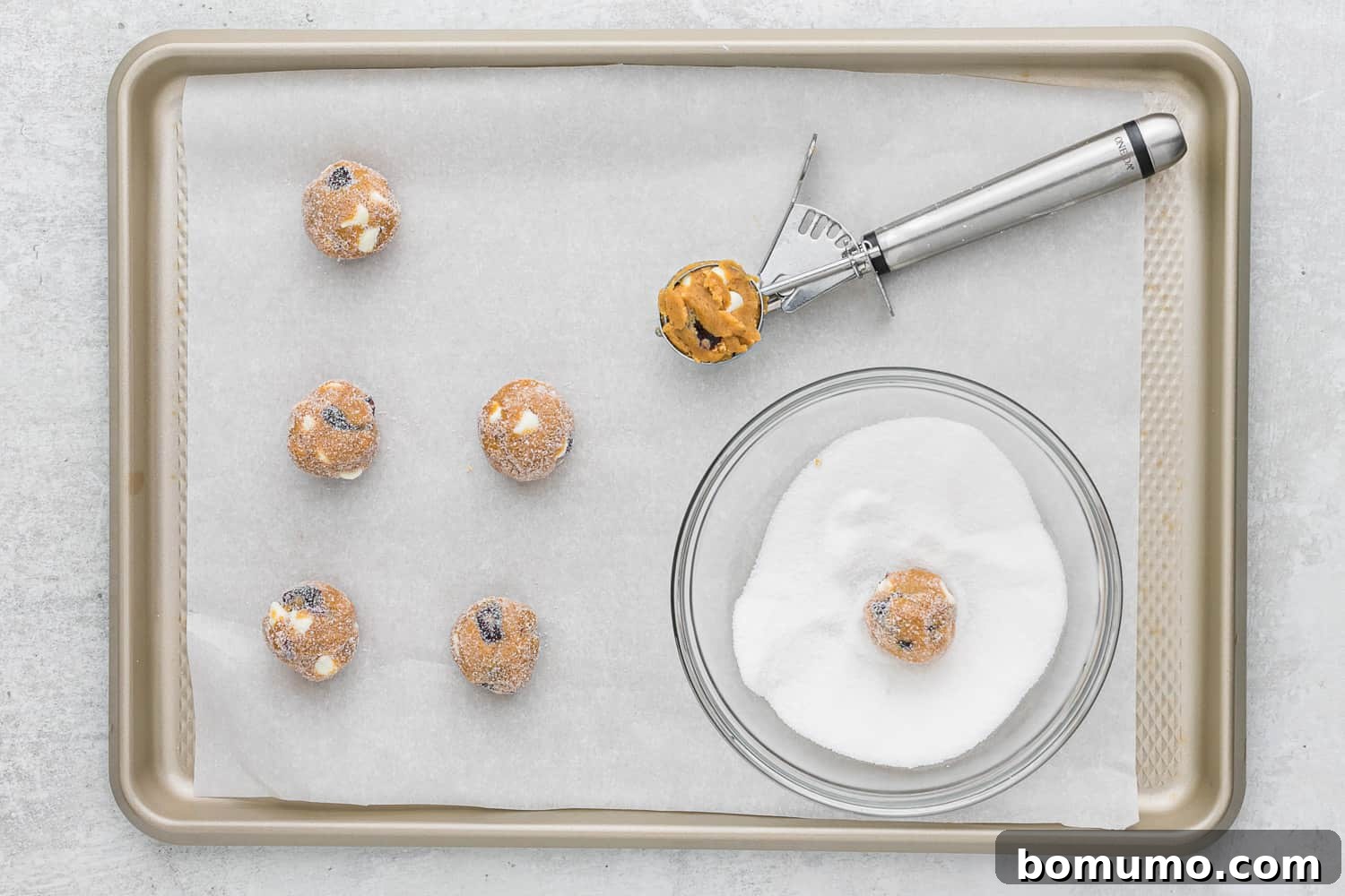 Unbaked gingersnap cookies, perfectly rolled in sugar and spaced on a baking sheet, ready for the oven.