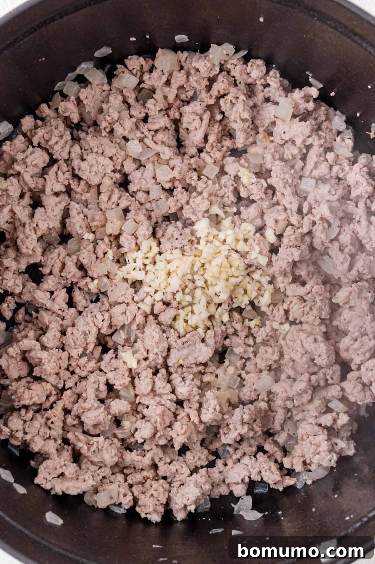 Deconstructed Cabbage Roll Soup 6 The savory mixture of browned ground meat and chopped onions cooking in a pan, with freshly minced garlic generously added on top, ready to infuse its pungent aroma into the dish.