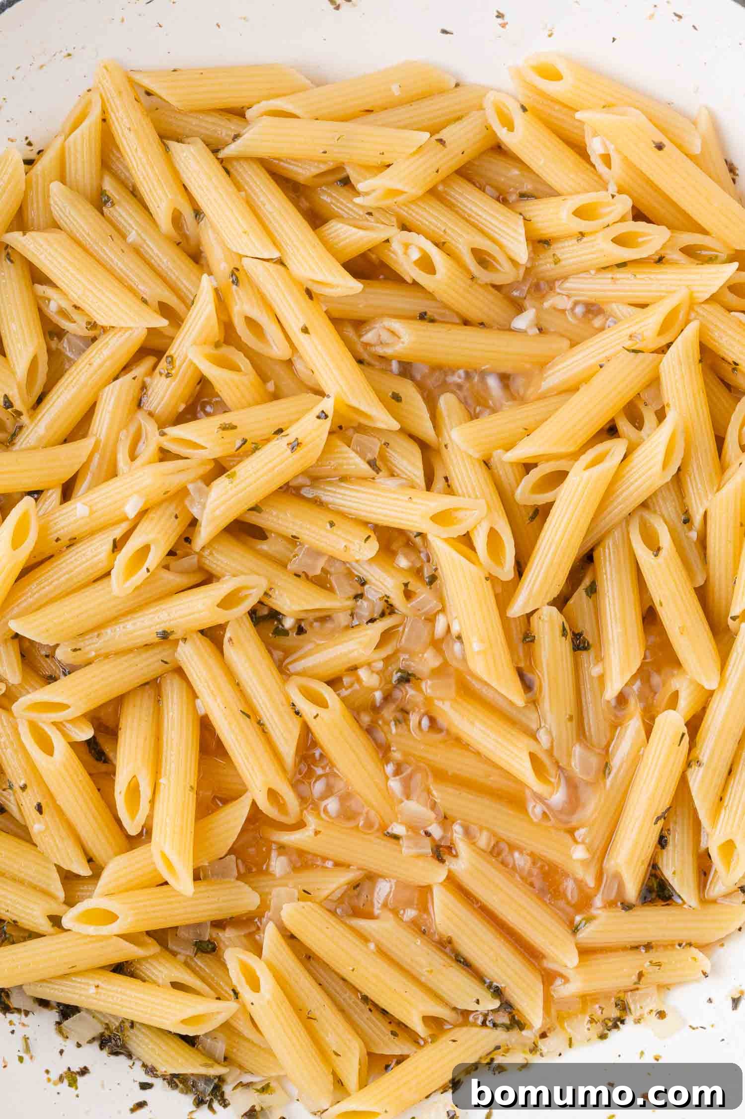Creamy Chicken Skillet Pasta 11 A delectable plate of cooked penne pasta, delicately coated in a light, savory sauce and garnished with fresh herbs, showcasing its tender texture and readiness for the next step.