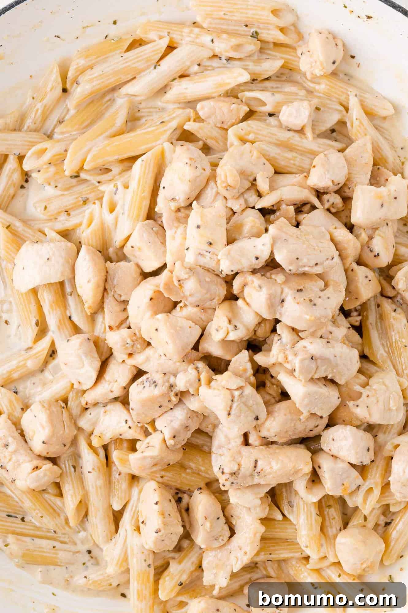 Creamy Chicken Skillet Pasta 13 Penne pasta interwoven with tender chunks of cooked chicken, all enveloped in a luxurious creamy sauce, exquisitely seasoned with fresh herbs and subtle spices, a truly inviting sight.